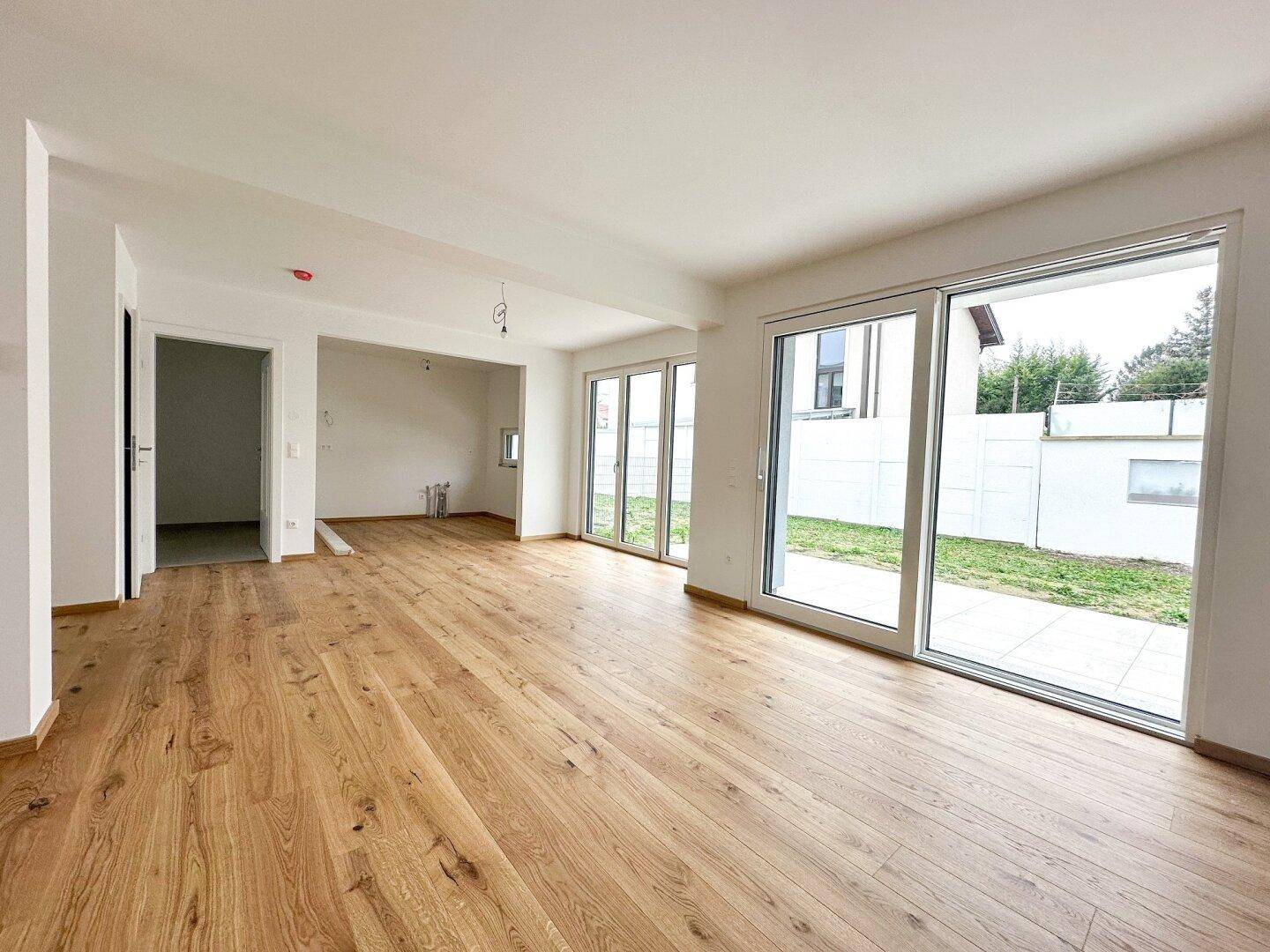 Lichtdurchfluteter Wohnbereich mit Holzboden und direktem Zugang zur Außenterrasse.