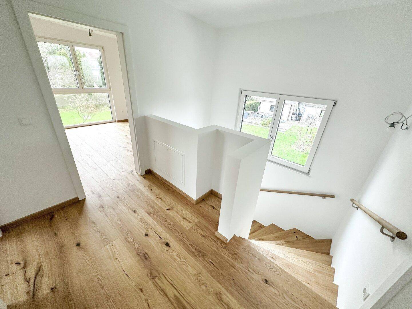 Treppenaufgang mit Holzstufen und Geländer, der zu den oberen Etagen führt.