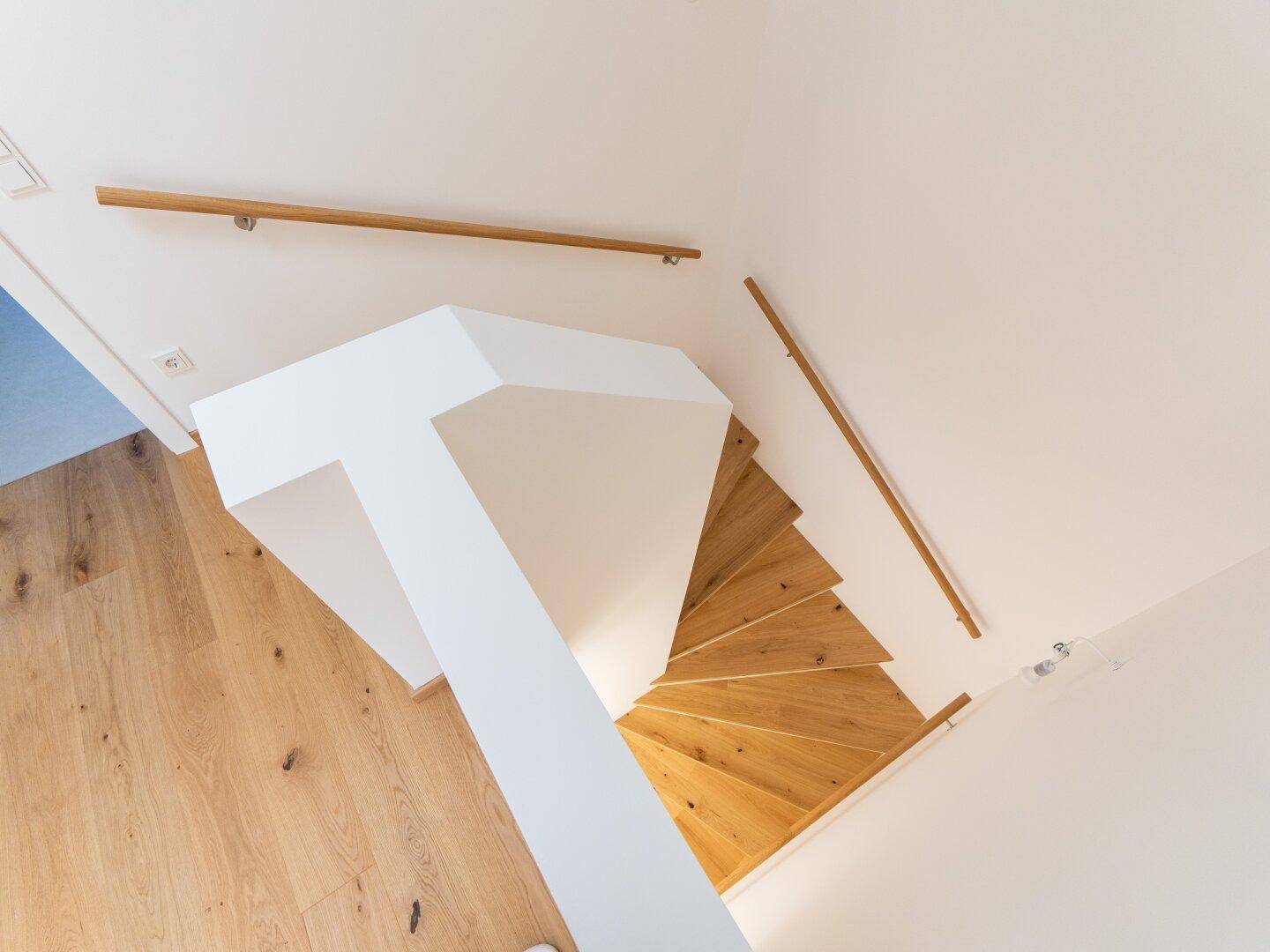 Moderne Holztreppe mit hellem Geländer, die die verschiedenen Etagen des Hauses verbindet.