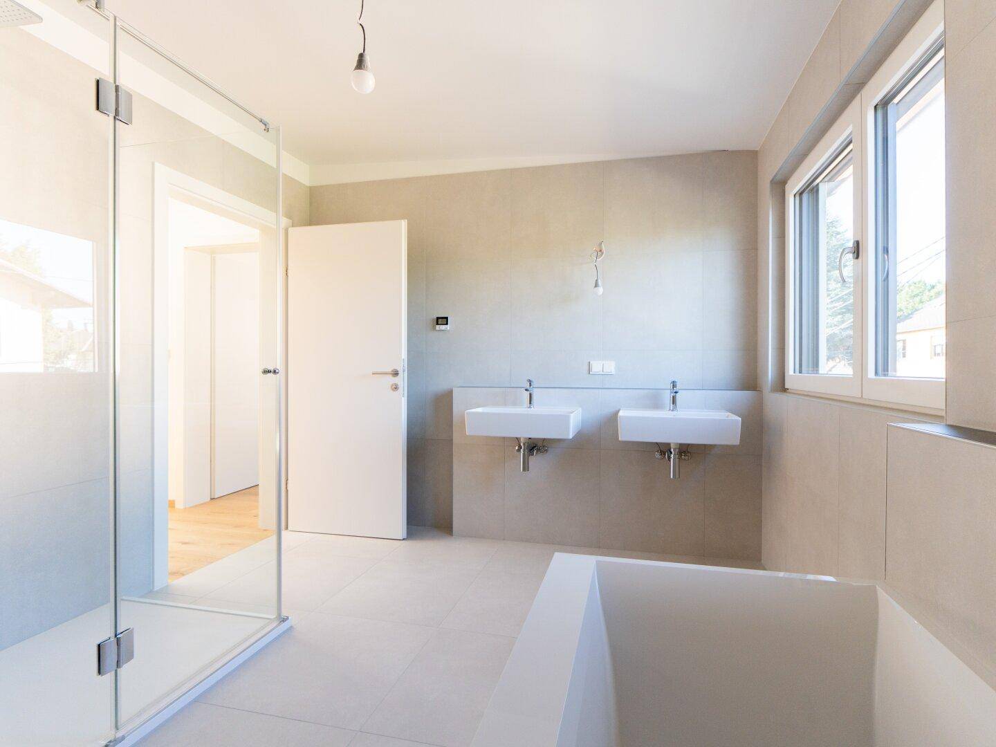 Modernes Badezimmer mit Doppelwaschbecken, Badewanne und großer begehbarer Dusche.