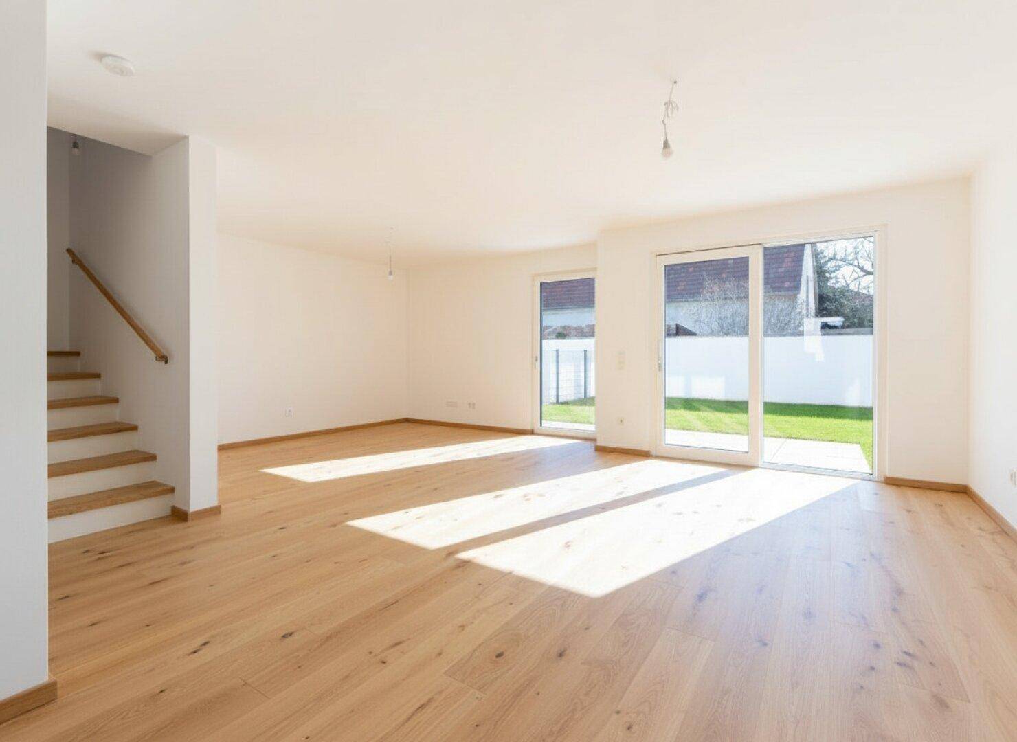 Helles, leeres Wohnzimmer mit Eichenparkettboden und Zugang zum Garten durch große Schiebetüren.