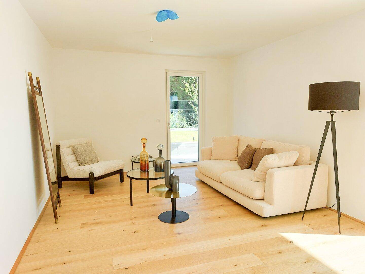 Helles Wohnzimmer mit beigem Sofa, modernem Dekor und Zugang zum Gartenbereich.