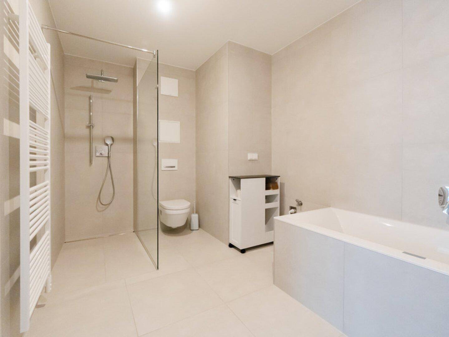 Modernes Badezimmer mit begehbarer Dusche, Badewanne und hellen Fliesen.
