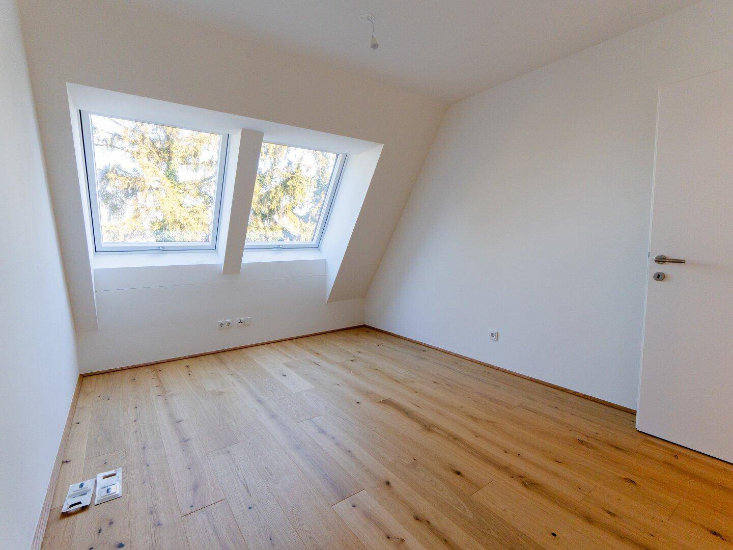 Geräumiges Zimmer mit Dachschrägen, Holzboden und hellen Dachfenstern, ideal für ein Schlafzimmer.