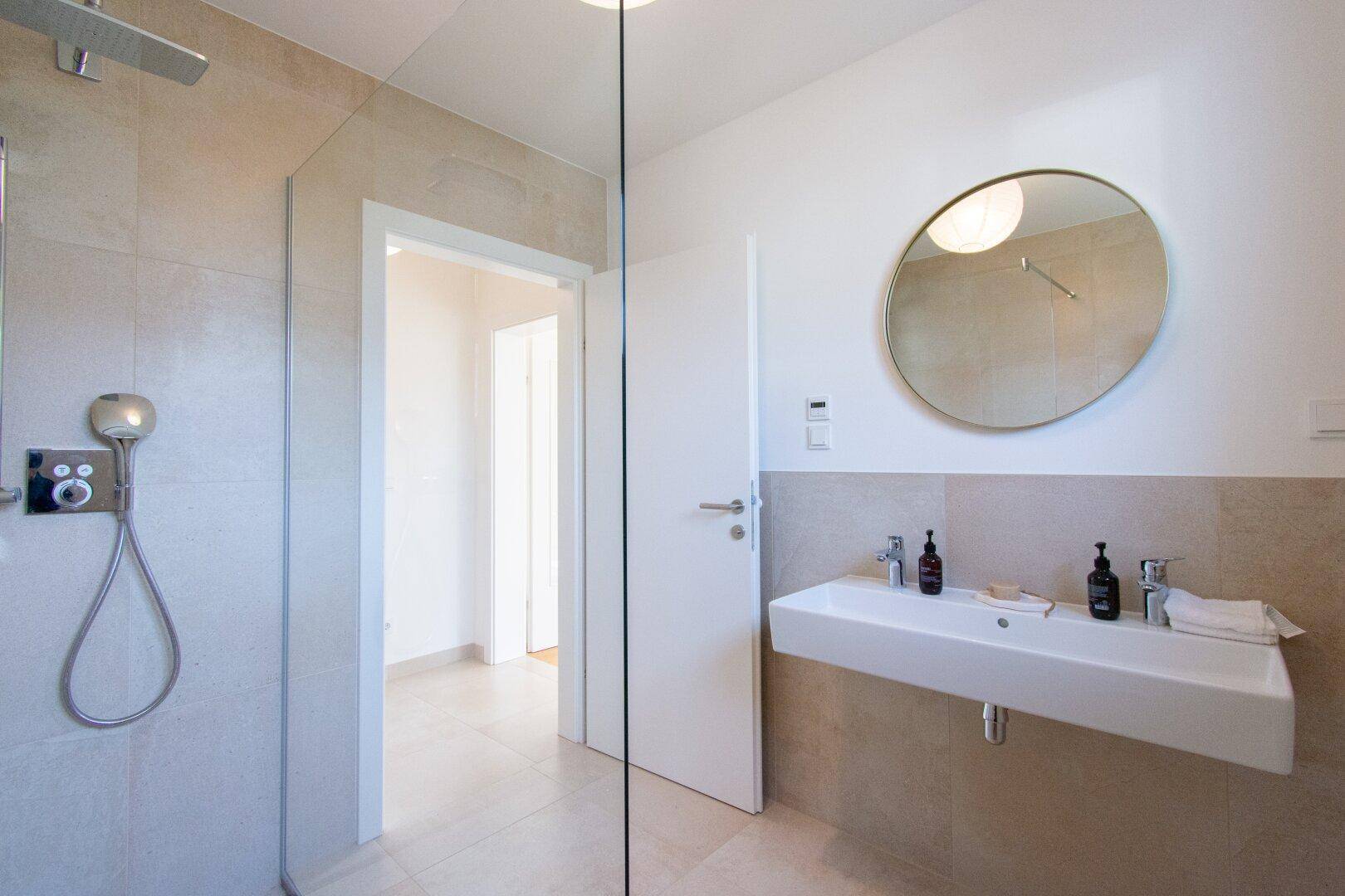 Modernes Badezimmer mit großem Waschbecken, Duschbereich und Spiegel.