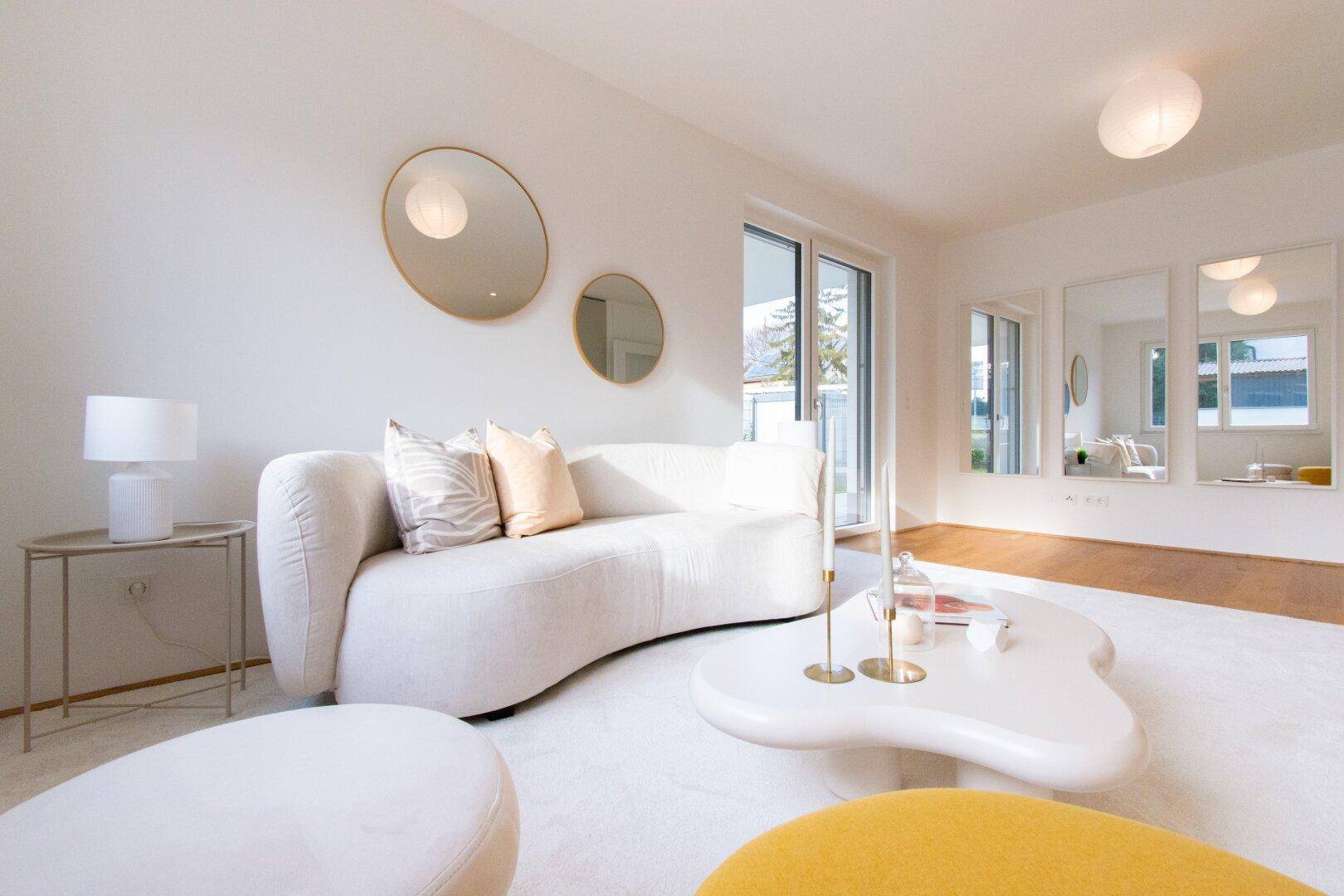 Helles Wohnzimmer mit modernem Sofa, Teppichboden und Zugang zur Terrasse.