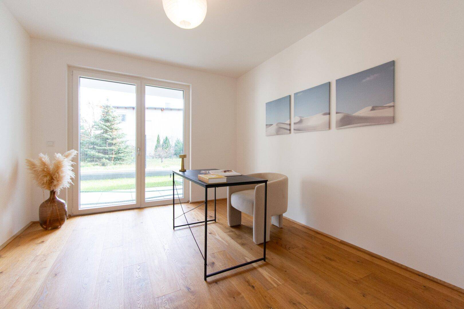 Helles Arbeitszimmer mit Schreibtisch, Stuhl und Zugang zum Garten.