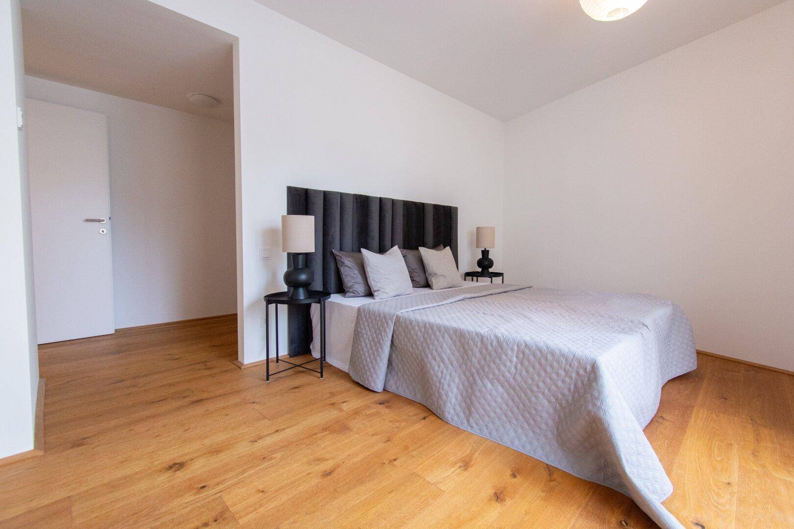 Geräumiges Schlafzimmer mit Holzboden, großem Bett und dunklem Kopfteil.
