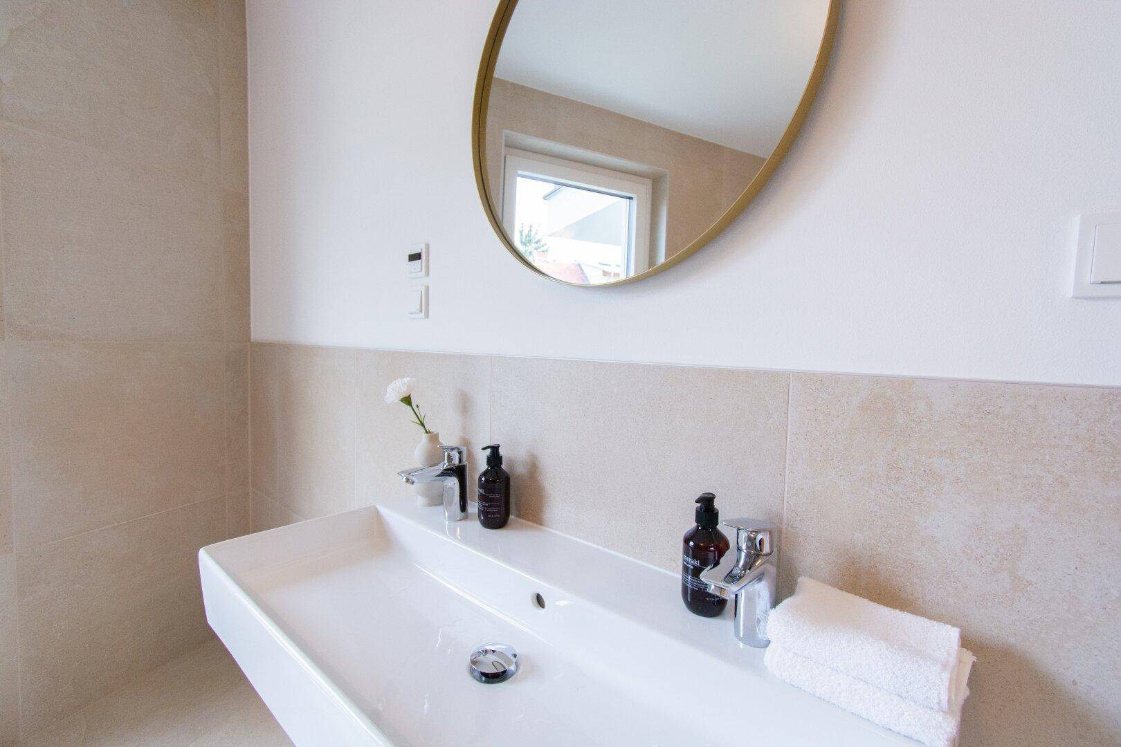 Modernes Badezimmer mit großem Waschbecken, Spiegel und Fenster.