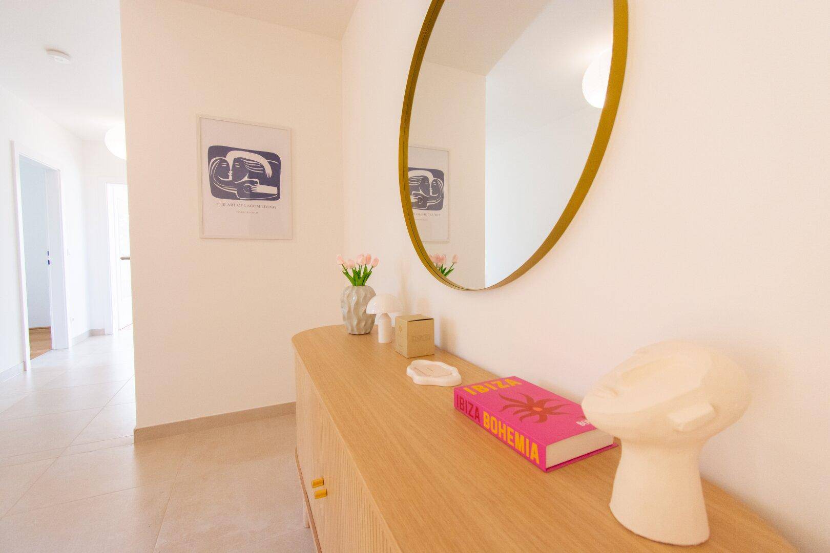 Heller Flur mit modernem Sideboard, Spiegel und Fliesenboden.