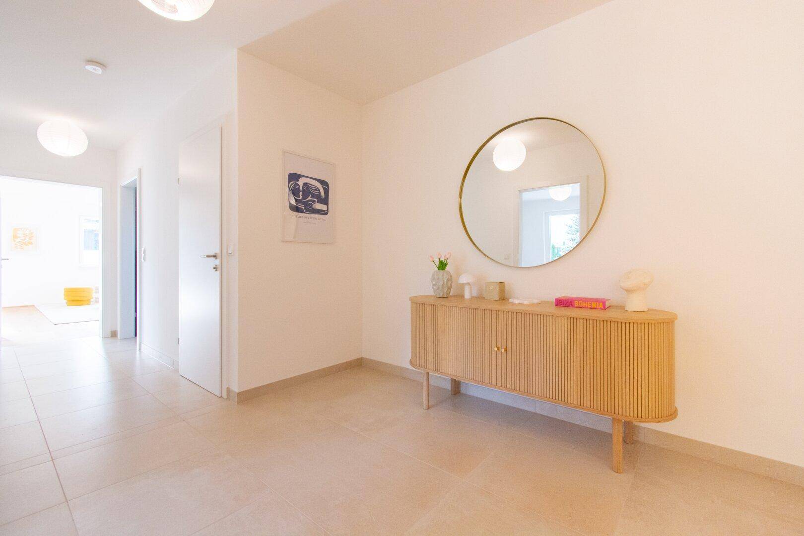 Heller Eingangsbereich mit modernem Sideboard, Spiegel und Fliesenboden.