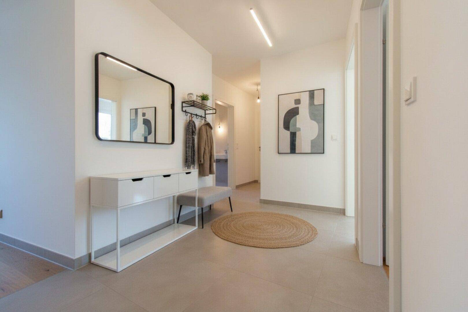 Moderner Flur mit Spiegel, Garderobe und hellem Fliesenboden, minimalistisch eingerichtet.