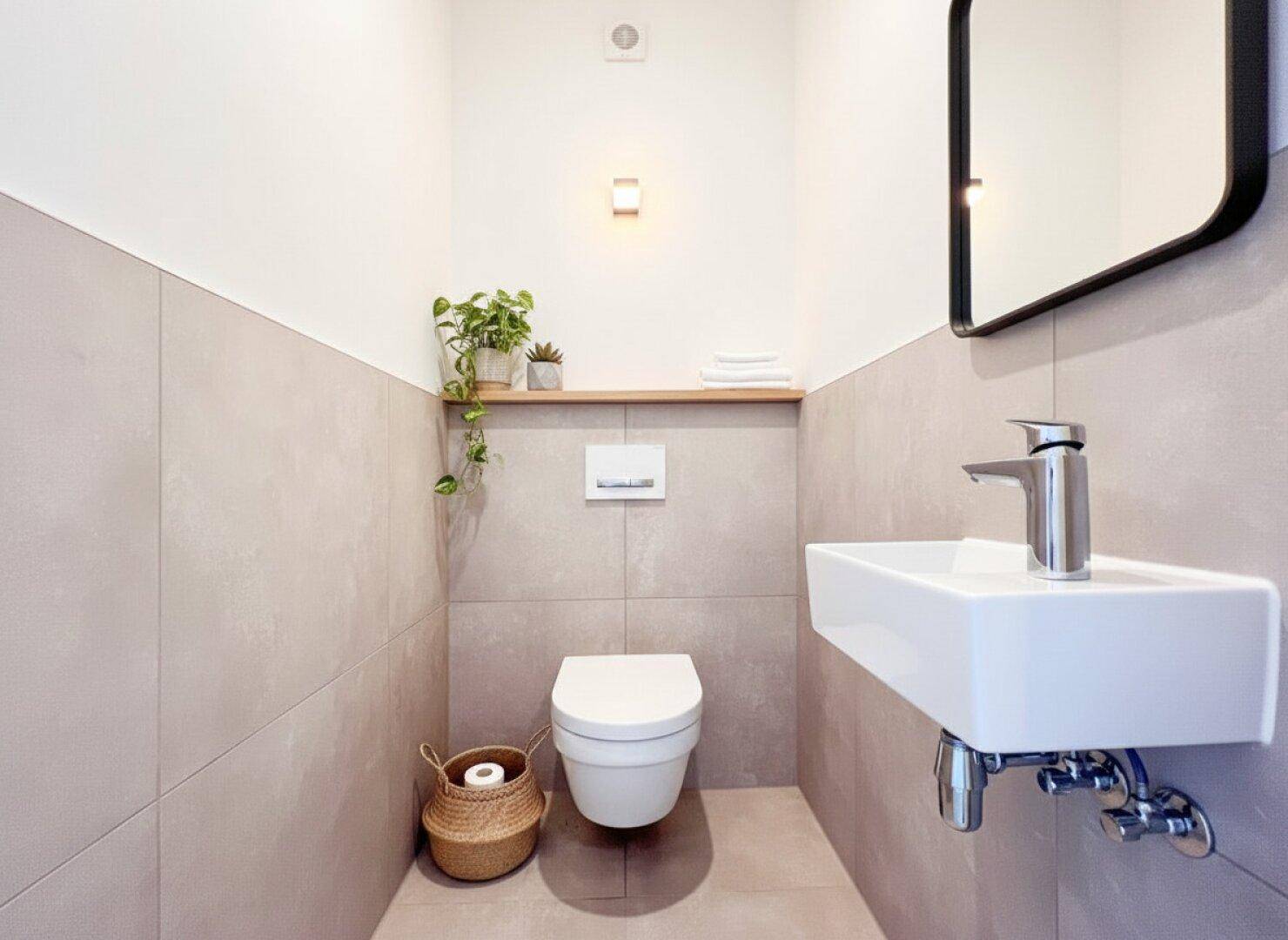 Kompaktes Gäste-WC mit Wand-WC, kleinem Waschbecken und modernen Fliesen.
