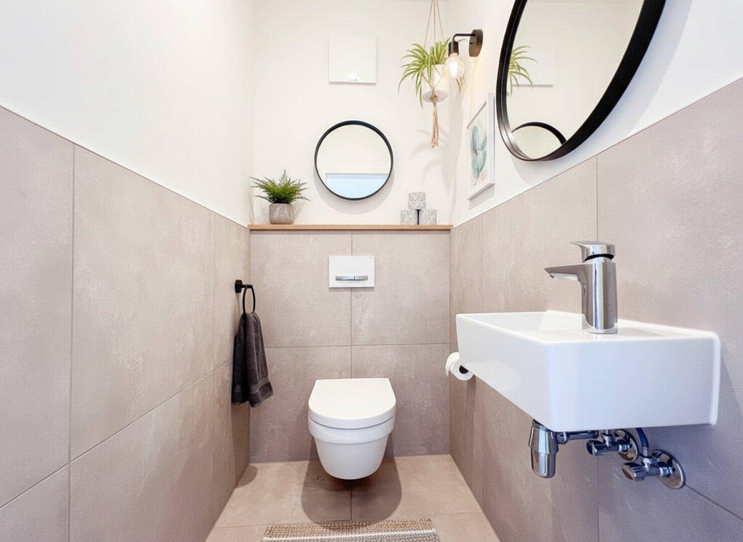 Modernes Gäste-WC mit Wand-WC, kleinem Waschbecken und stilvollen Wandfliesen.