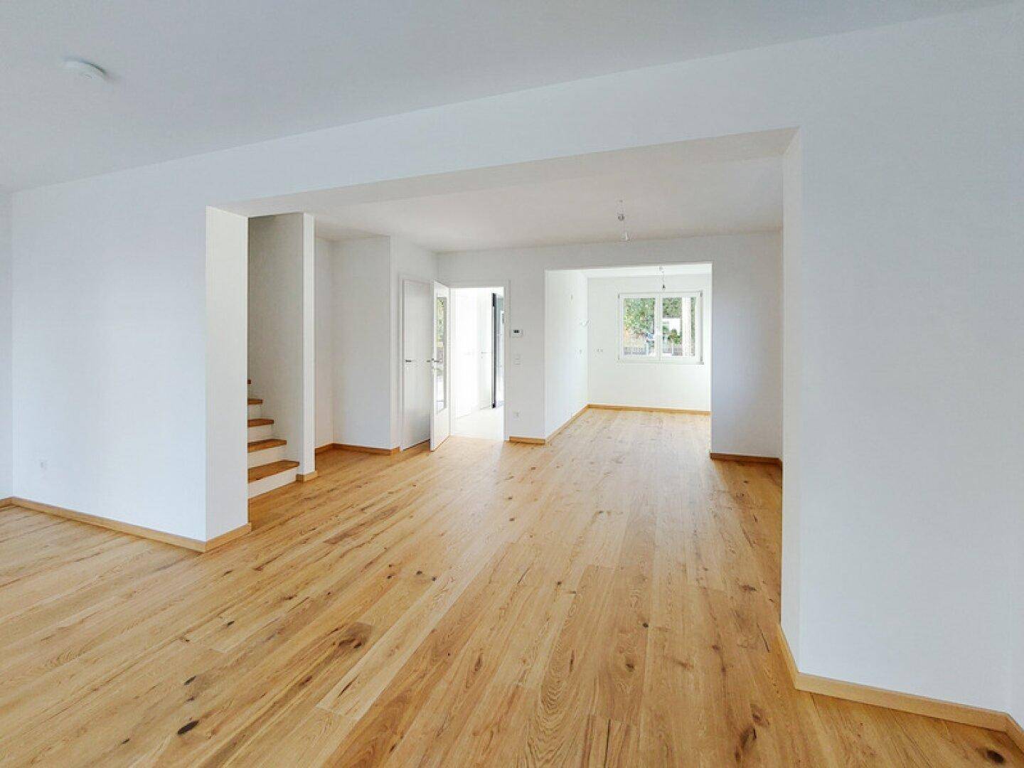 Geräumiger, offener Wohnbereich mit hellem Holzboden und viel Tageslicht.