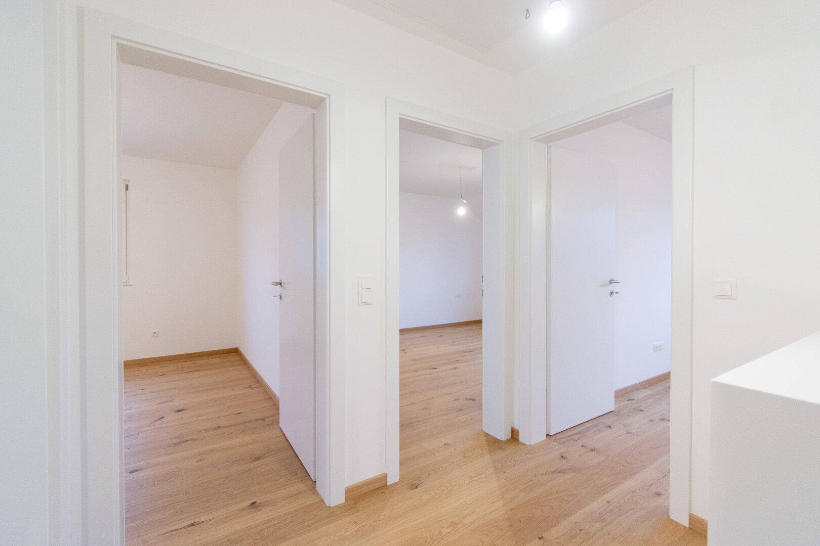 Heller Flur mit Holzparkettboden, der zu verschiedenen Zimmern im Obergeschoss führt.