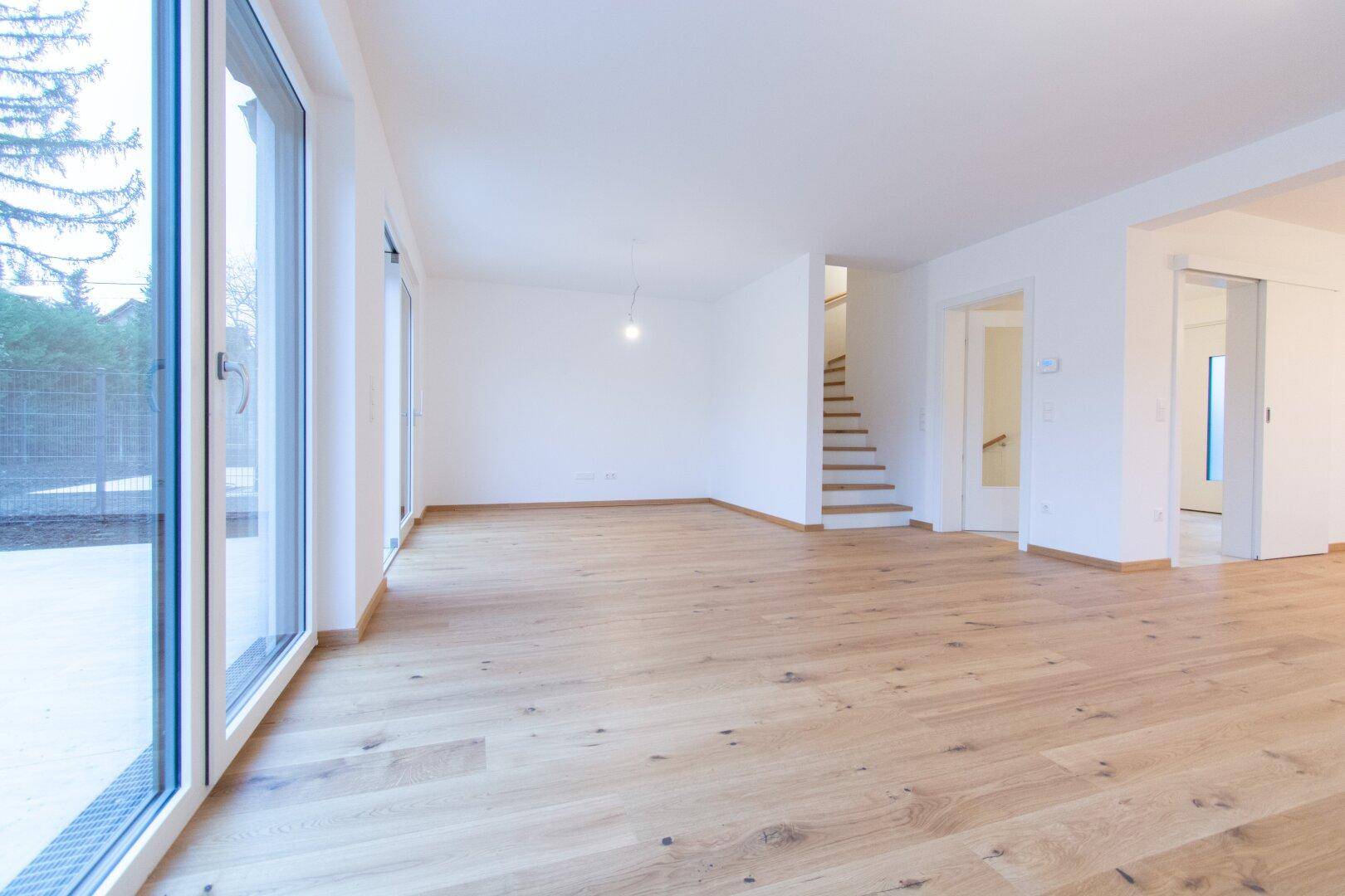Helles, geräumiges Wohnzimmer mit neuem Holzparkettboden und großen Fenstern zum Garten.