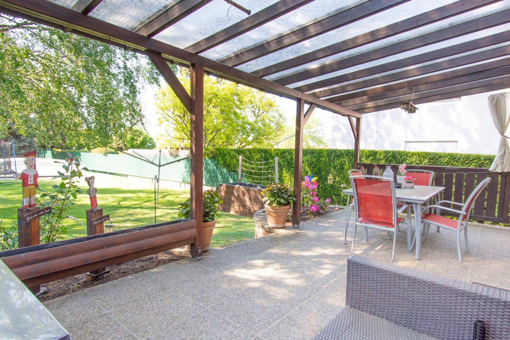Gemütliche überdachte Terrasse mit Gartenmöbeln und Blick ins Grüne, ideal für entspannte Stunden.