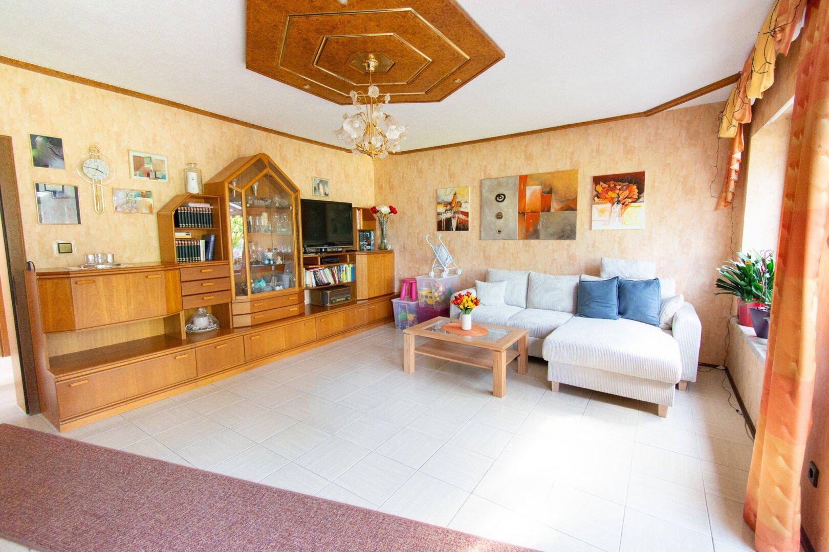 Gemütliches Wohnzimmer mit Fliesenboden, bequemer Couch und traditionellen Holzmöbeln.