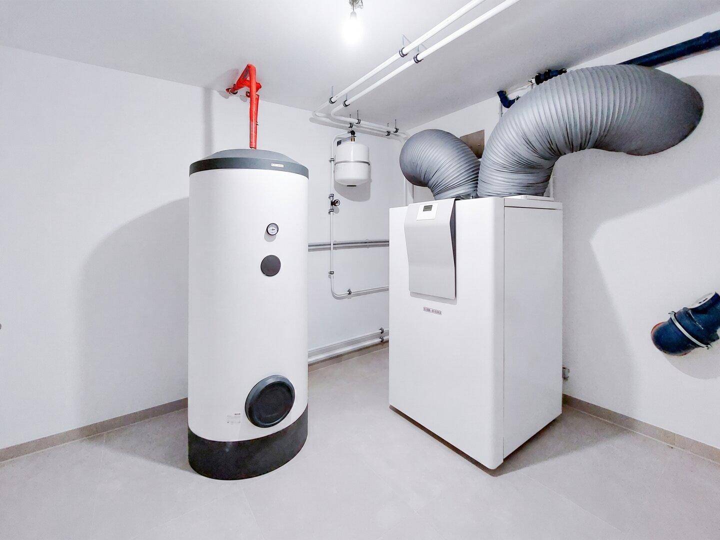 Technikraum mit Warmwasserspeicher und moderner Heizungsanlage für das Gebäude.