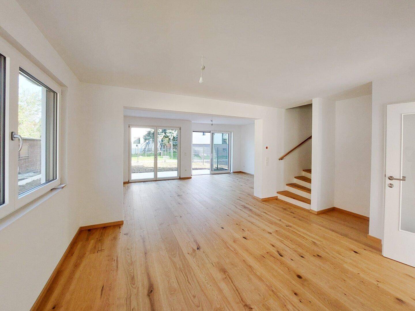 Geräumiger, heller Wohnbereich mit Holzparkett und großen Schiebetüren zum Garten.