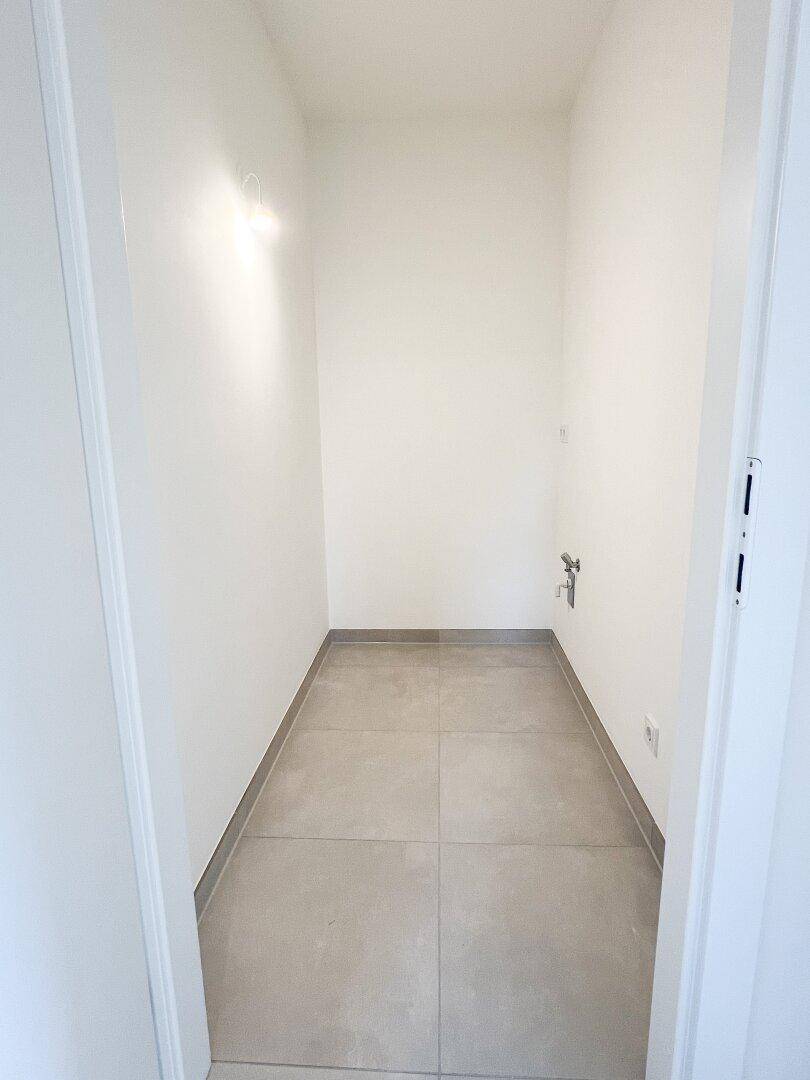 Kleiner Abstellraum mit Fliesenboden und Anschlüssen, ideal für Waschmaschine oder Lagerung.