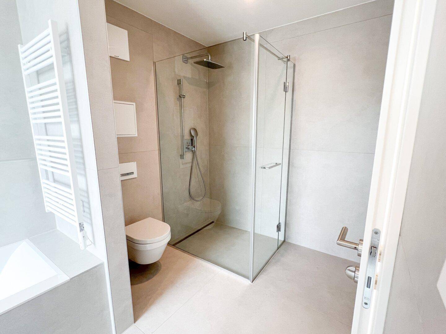 Elegantes Badezimmer mit begehbarer Dusche, Wand-WC und beheiztem Handtuchhalter in modernem Design.