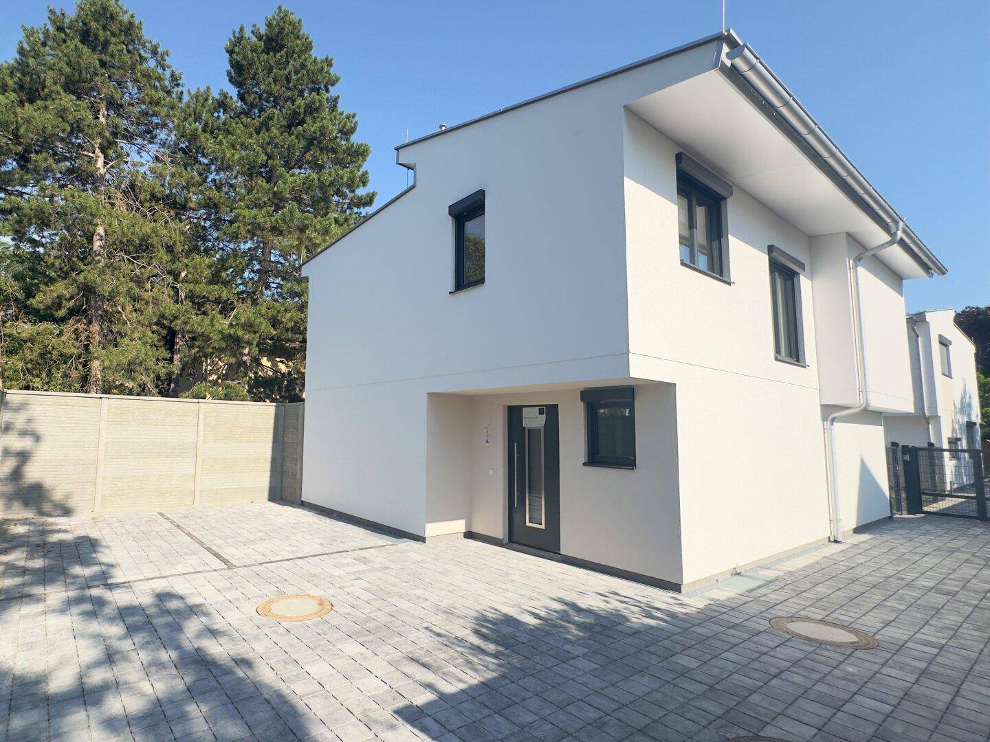 Vorderansicht des modernen Einfamilienhauses mit gepflastertem Stellplatz.
