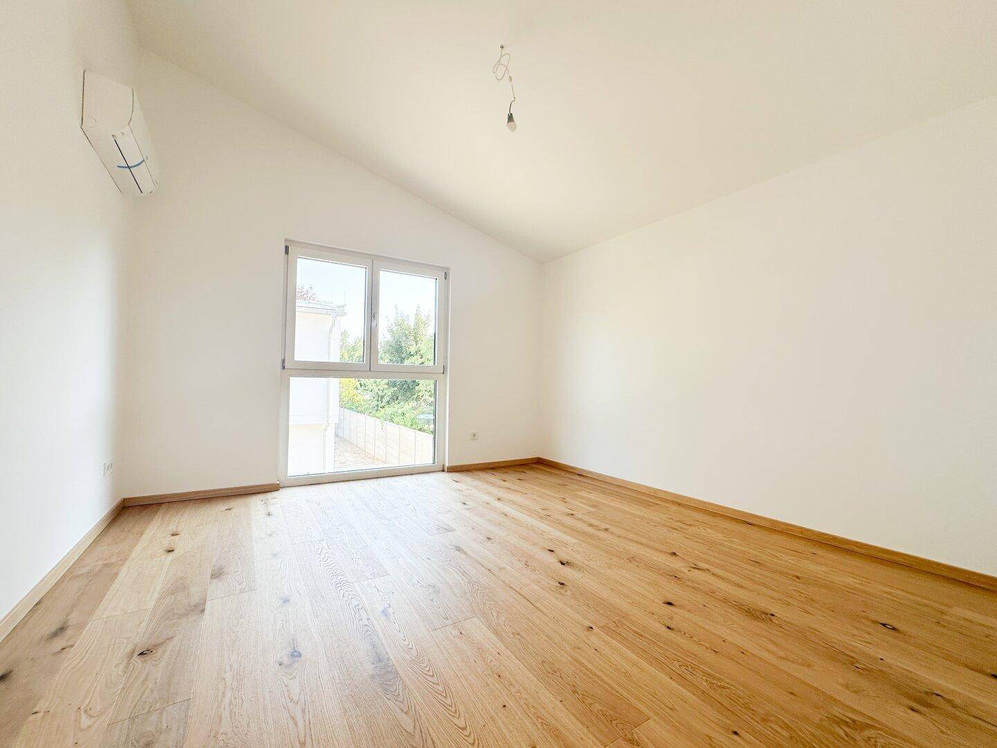 Helles Schlafzimmer mit Dachschräge, Eichenparkett und Klimaanlage.