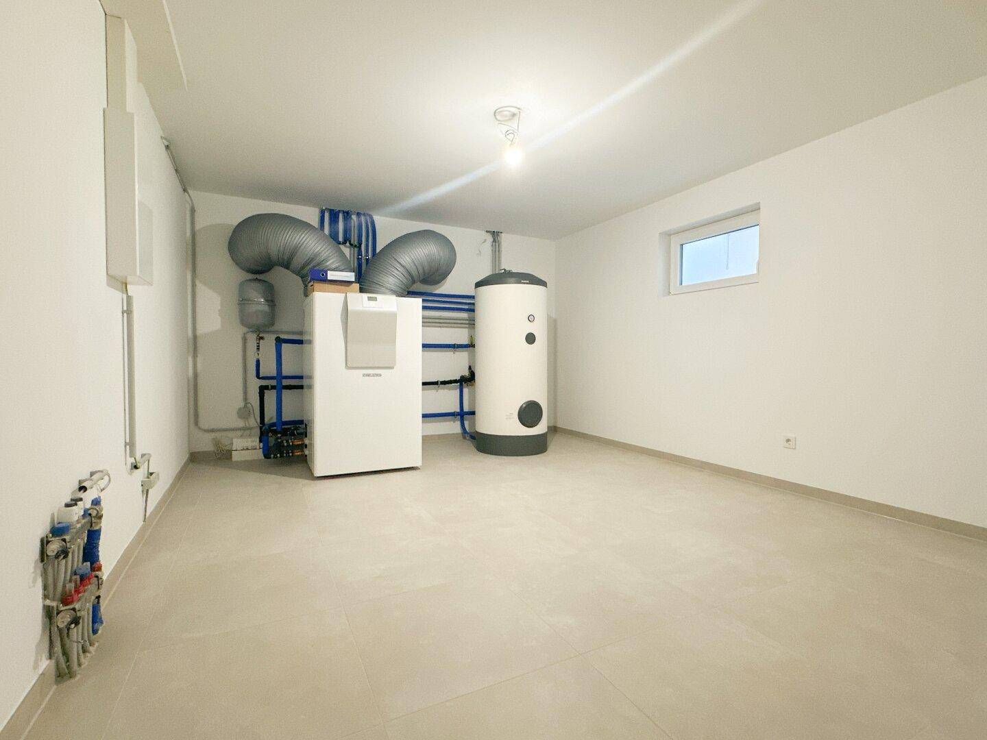 Technikraum im Keller mit Heizungsanlage und Warmwasserspeicher.