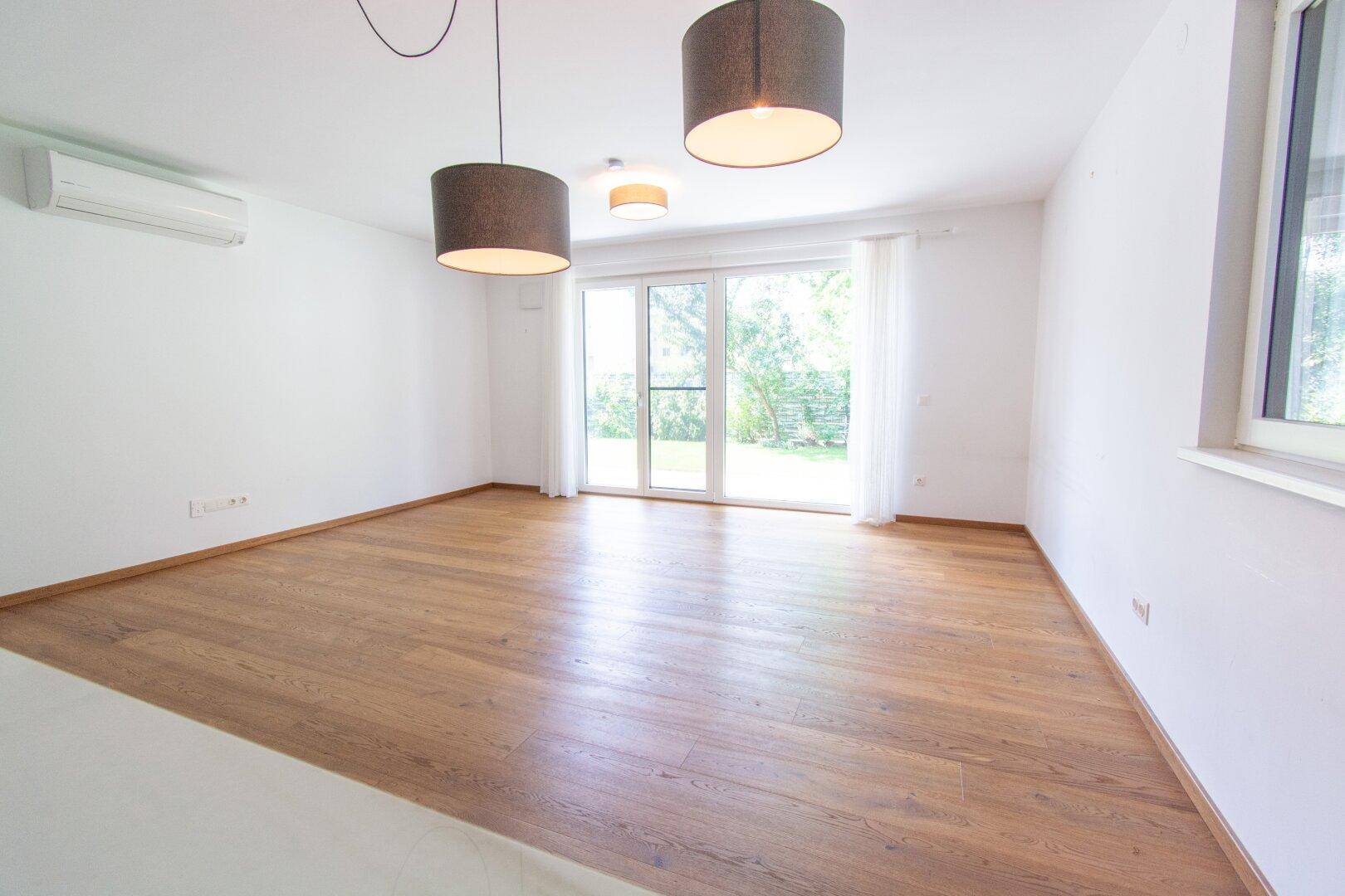 Helles Wohnzimmer mit Holzboden, großen Fenstern und Zugang zur Terrasse oder Garten.