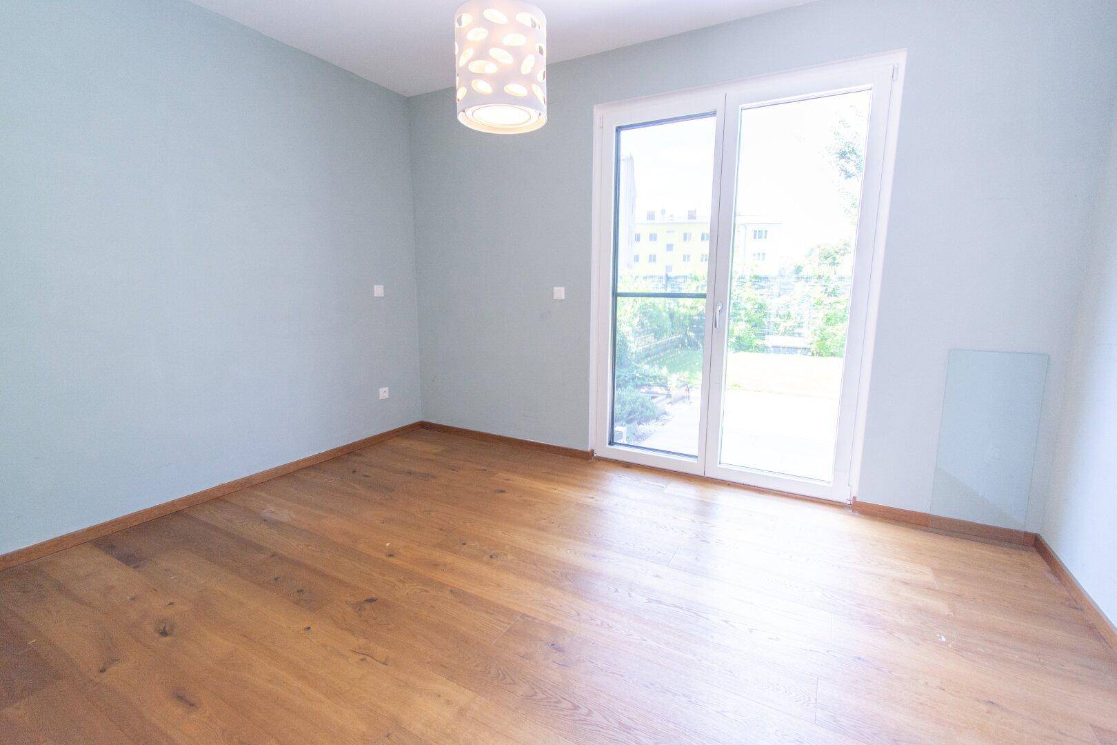 Schlafzimmer mit hellblauen Wänden, Holzboden und Zugang zu einem Außenbereich.