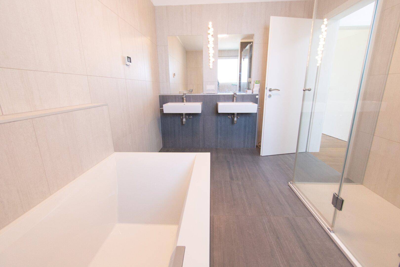 Modernes Badezimmer mit Badewanne, Doppelwaschbecken und begehbarer Dusche.