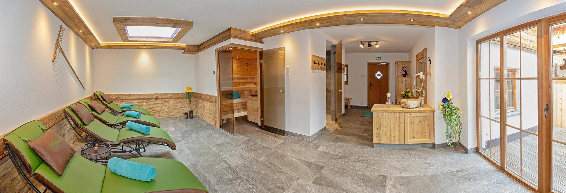 Entspannungsbereich mit Liegen, Sauna und großen Fenstern für viel Tageslicht.