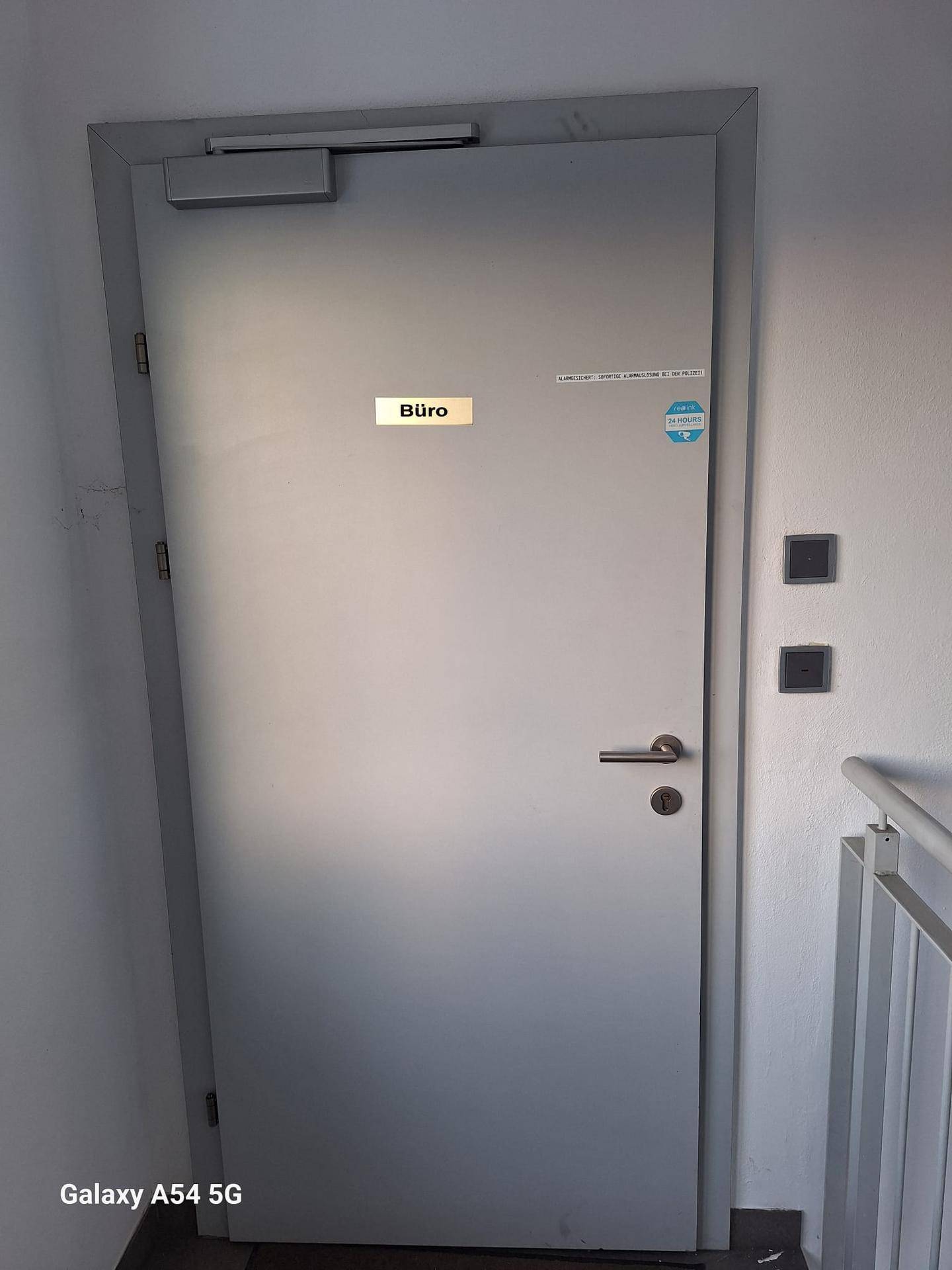 Eine schlichte graue Bürotür mit einem Schild, das den Raum als Büro kennzeichnet.
