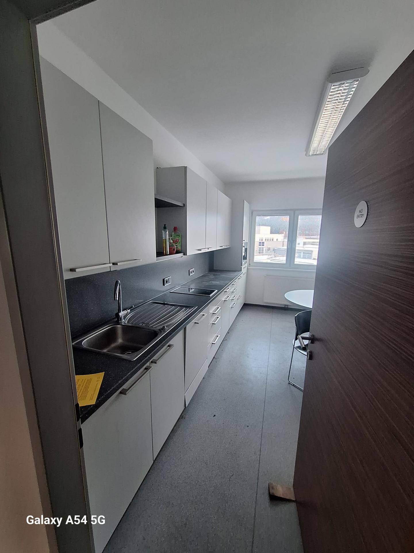 Funktionale Küchenzeile mit weißen Schränken, dunklen Arbeitsplatten und zwei Spülbecken unter einem Fenster.