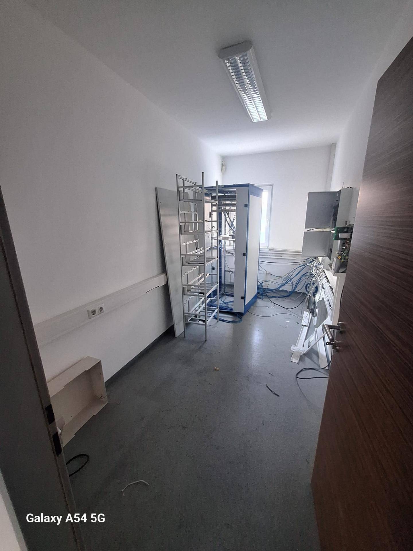 Technikraum mit Serverracks, Verkabelung und einem Fenster, das für Belüftung und Licht sorgt.