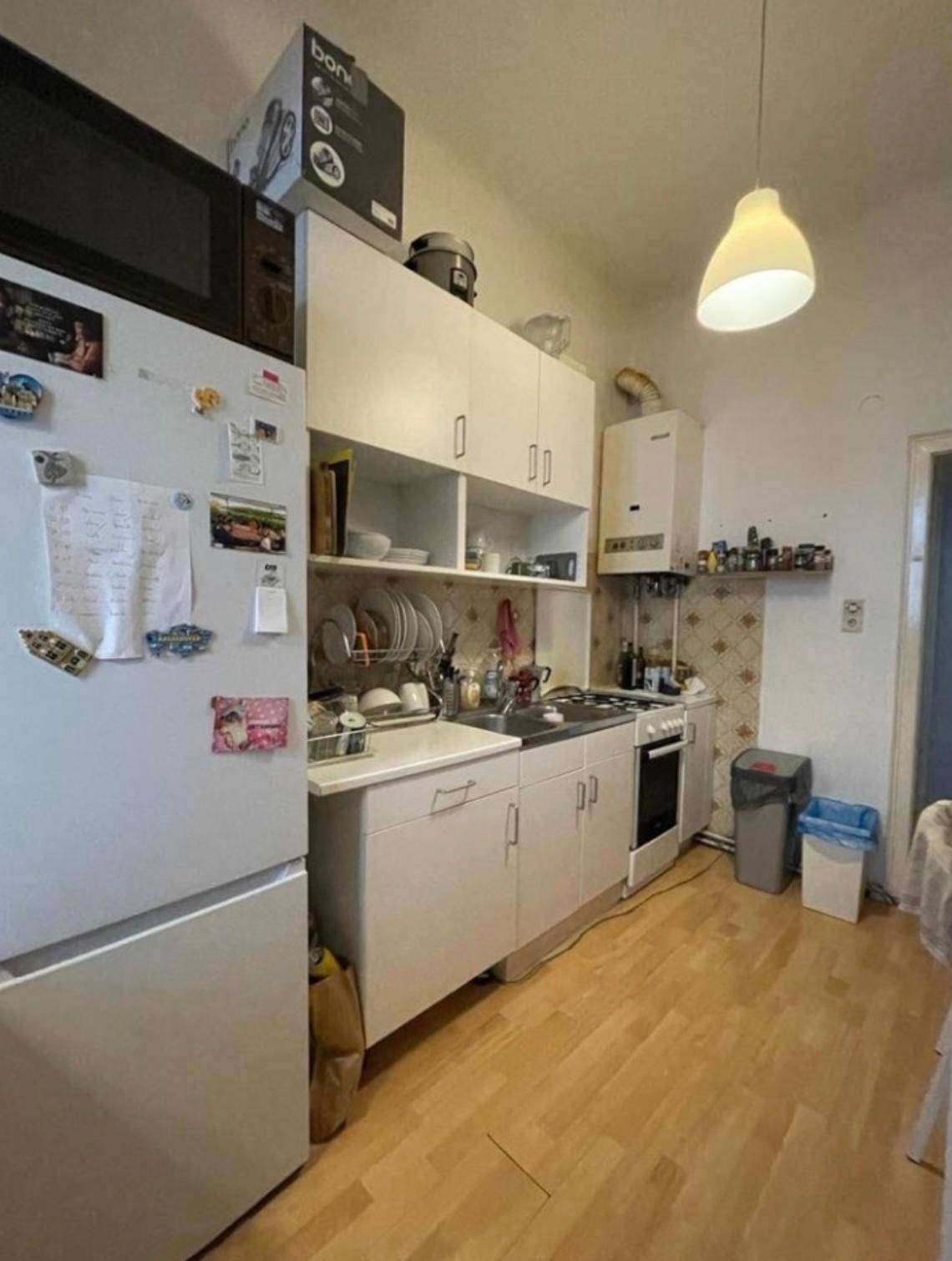 Kleine Küche mit weißen Schränken, Gasherd und Kühlschrank.