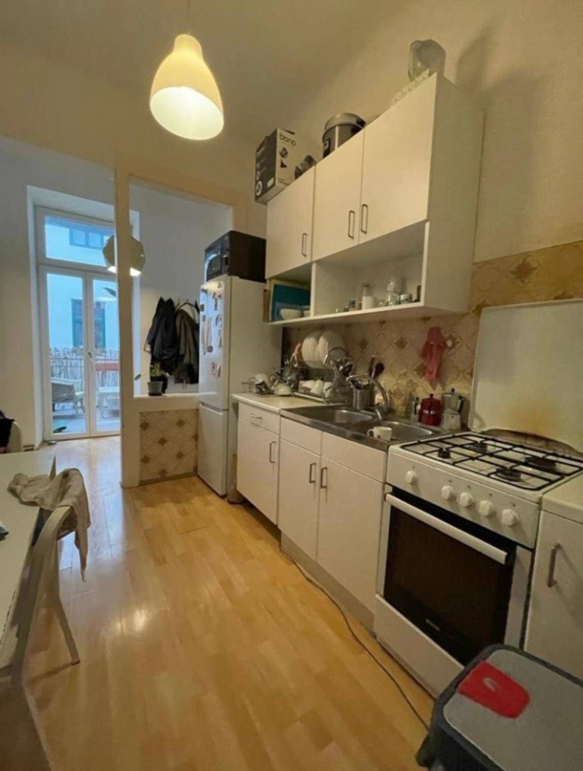 Funktionale Küche mit Gasherd, Kühlschrank und Zugang zu einem kleinen Balkon.