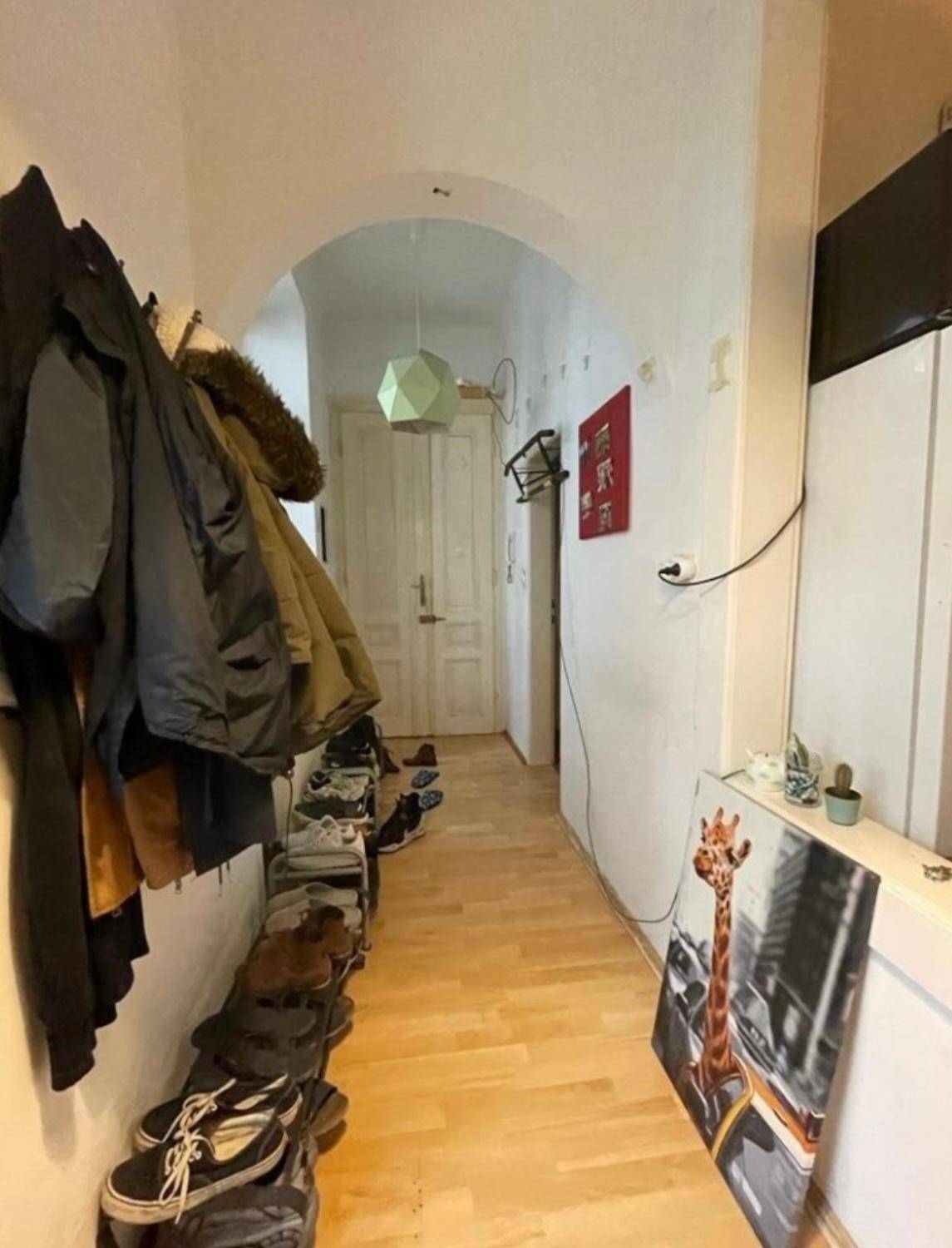 Langer Flur mit Garderobe, Schuhregal und hellem Holzfußboden.