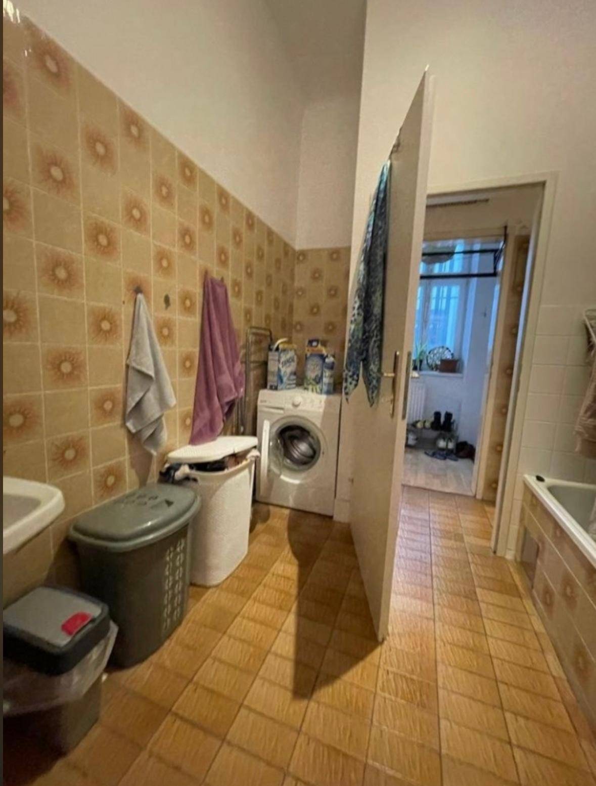 Badezimmer mit Waschmaschine, Waschbecken und Fliesen im Retro-Stil.