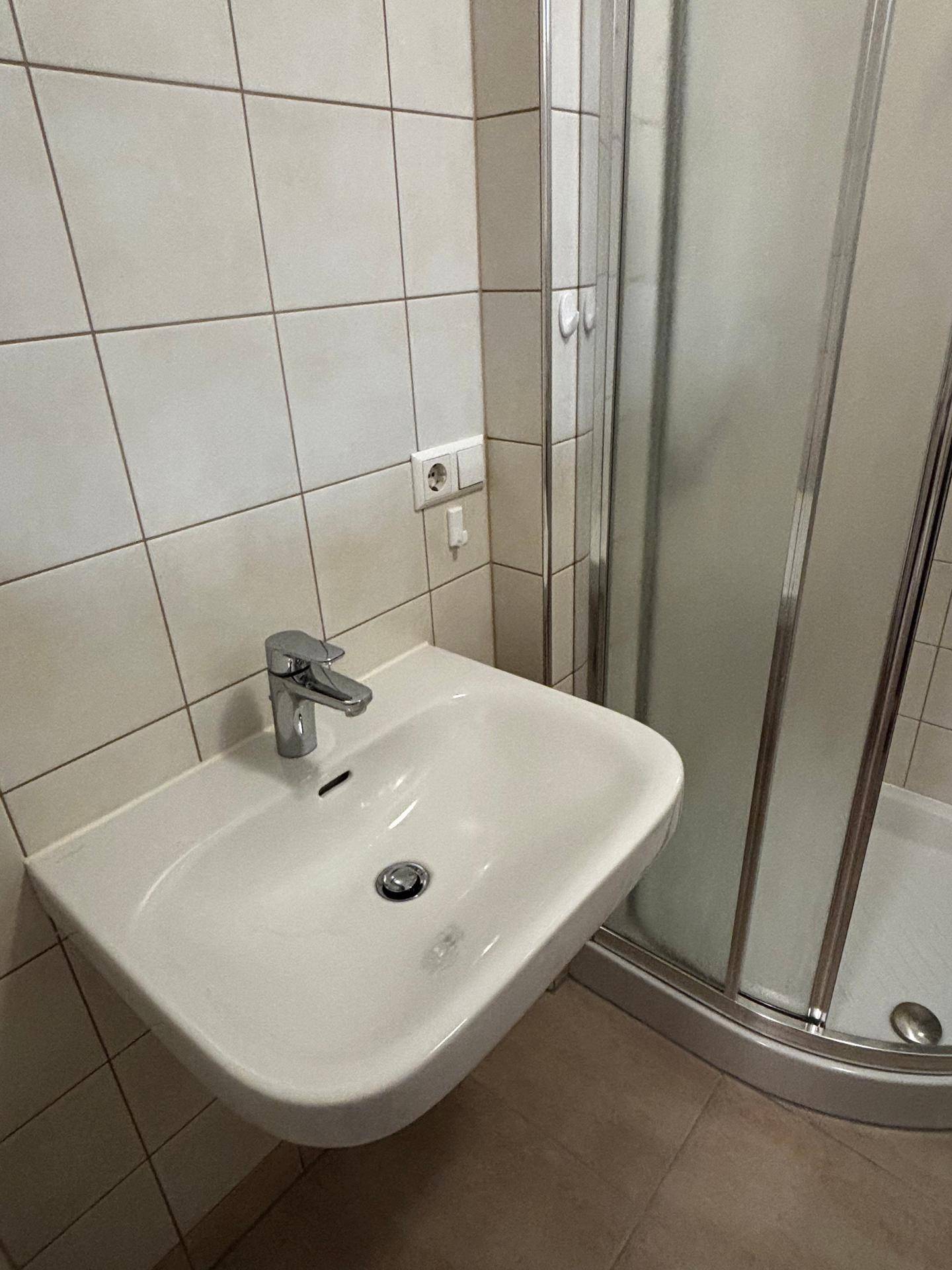 Nahaufnahme des Waschbeckens im Badezimmer mit Fliesen und moderner Armatur.