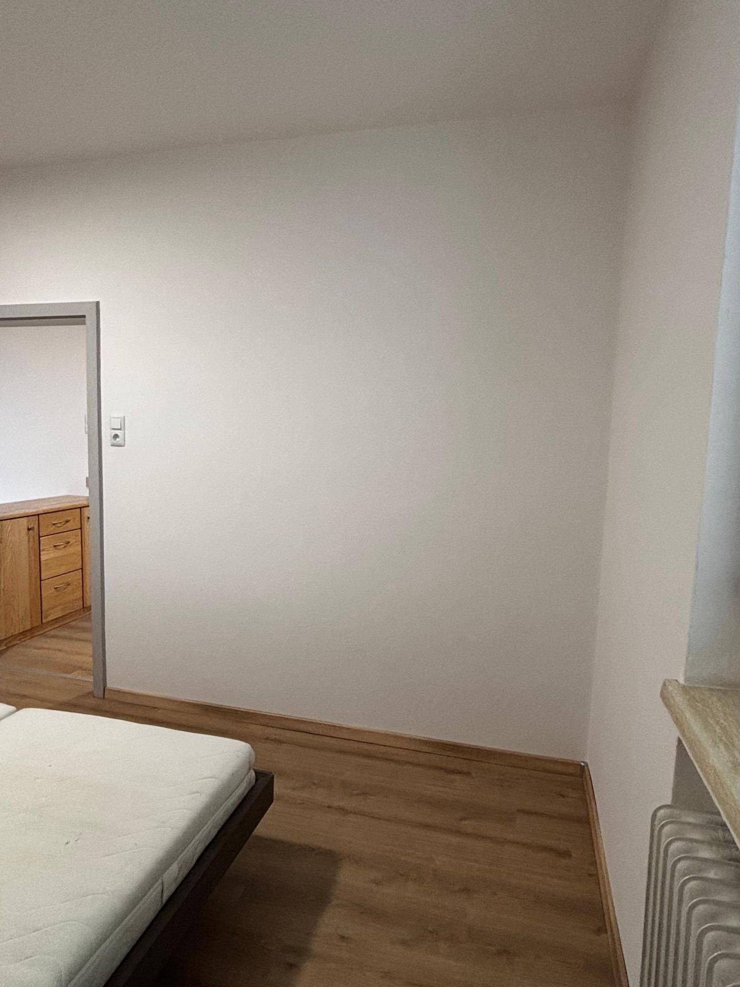 Schlafzimmer mit Laminatboden und weiß gestrichenen Wänden, bereit zur Einrichtung.