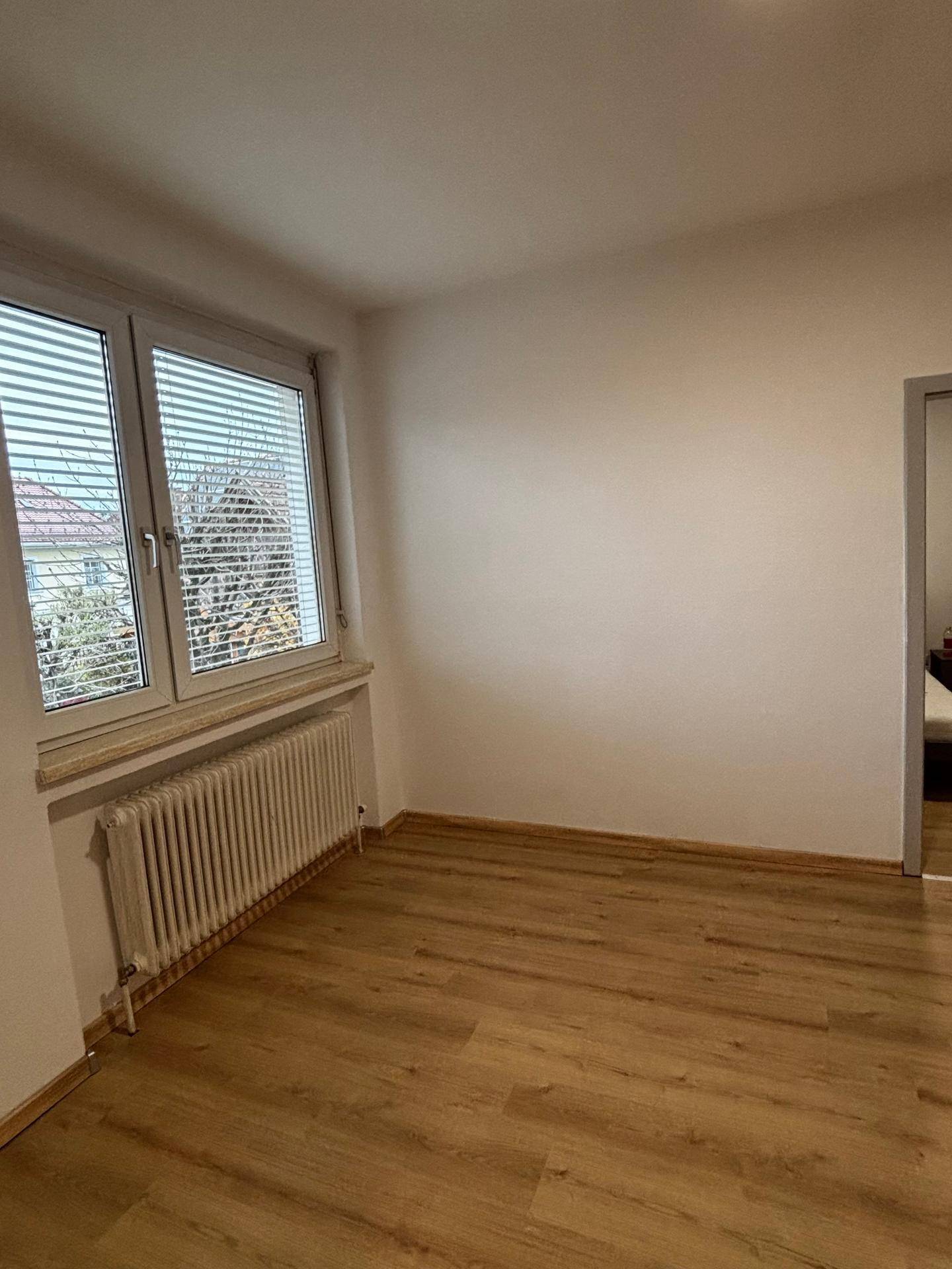 Geräumiges Zimmer mit Laminatboden und Fenster, das viel Tageslicht hereinlässt.