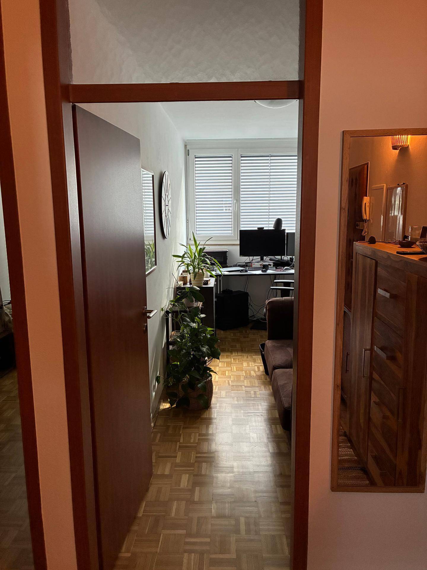 Blick in ein helles Zimmer, eingerichtet als Büro mit Schreibtisch und bequemer Sitzgelegenheit.
