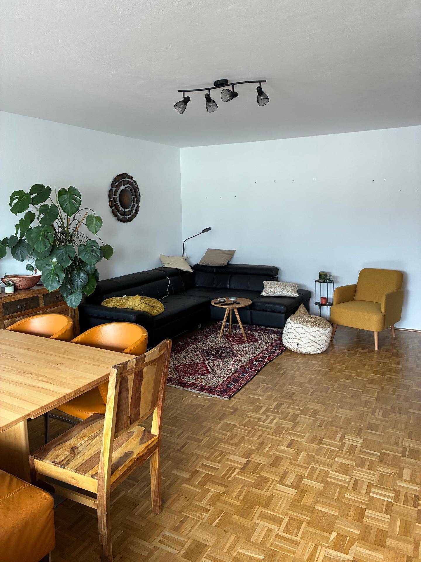 Geräumiger Wohn-Essbereich mit Ecksofa, Esstisch und hellem Holzparkettboden.
