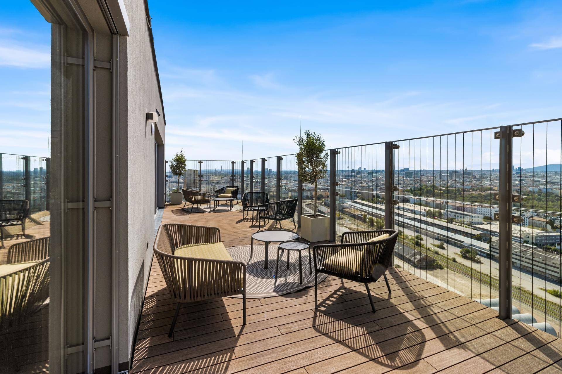 Geräumige Dachterrasse mit Holzboden, Sitzgelegenheiten und weitem Stadtblick.