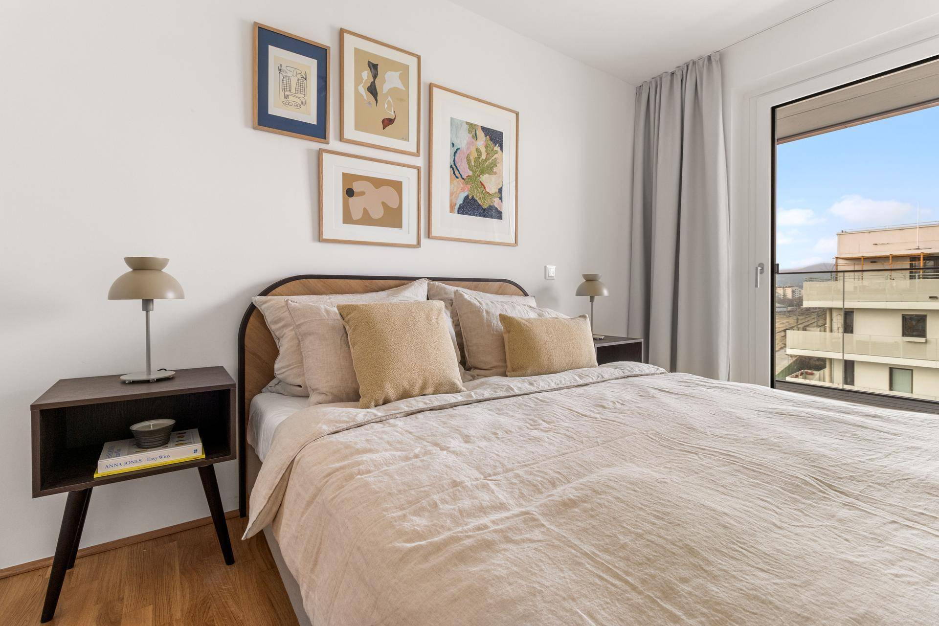 Gemütliches Schlafzimmer mit Holzboden, modernen Bildern und Zugang zu einem Balkon oder einer Terrasse.