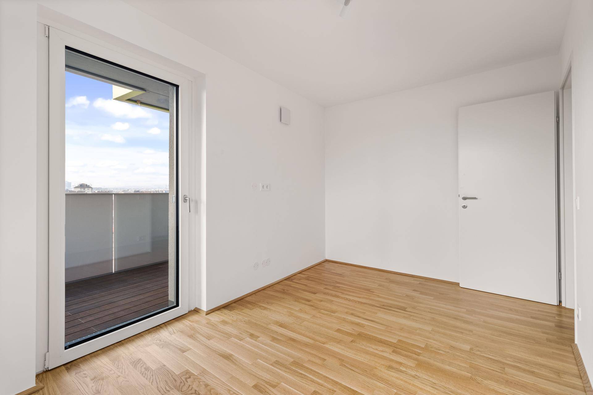 Geräumiges Zimmer mit Parkettboden und Zugang zu einem Balkon, ideal für individuelle Gestaltung.