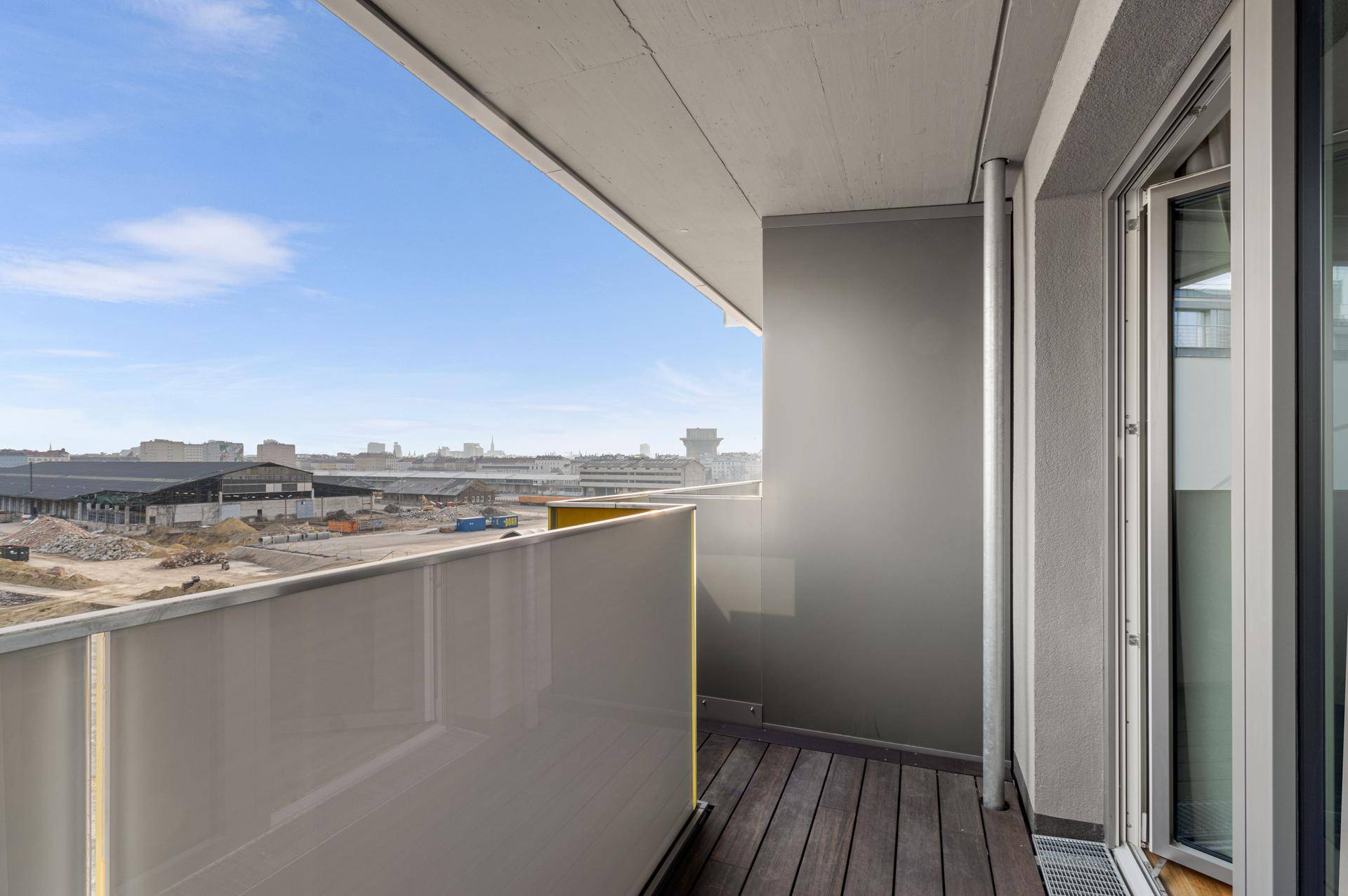 Balkon mit Holzboden und weitem Blick über die städtische Umgebung und Baustellen.